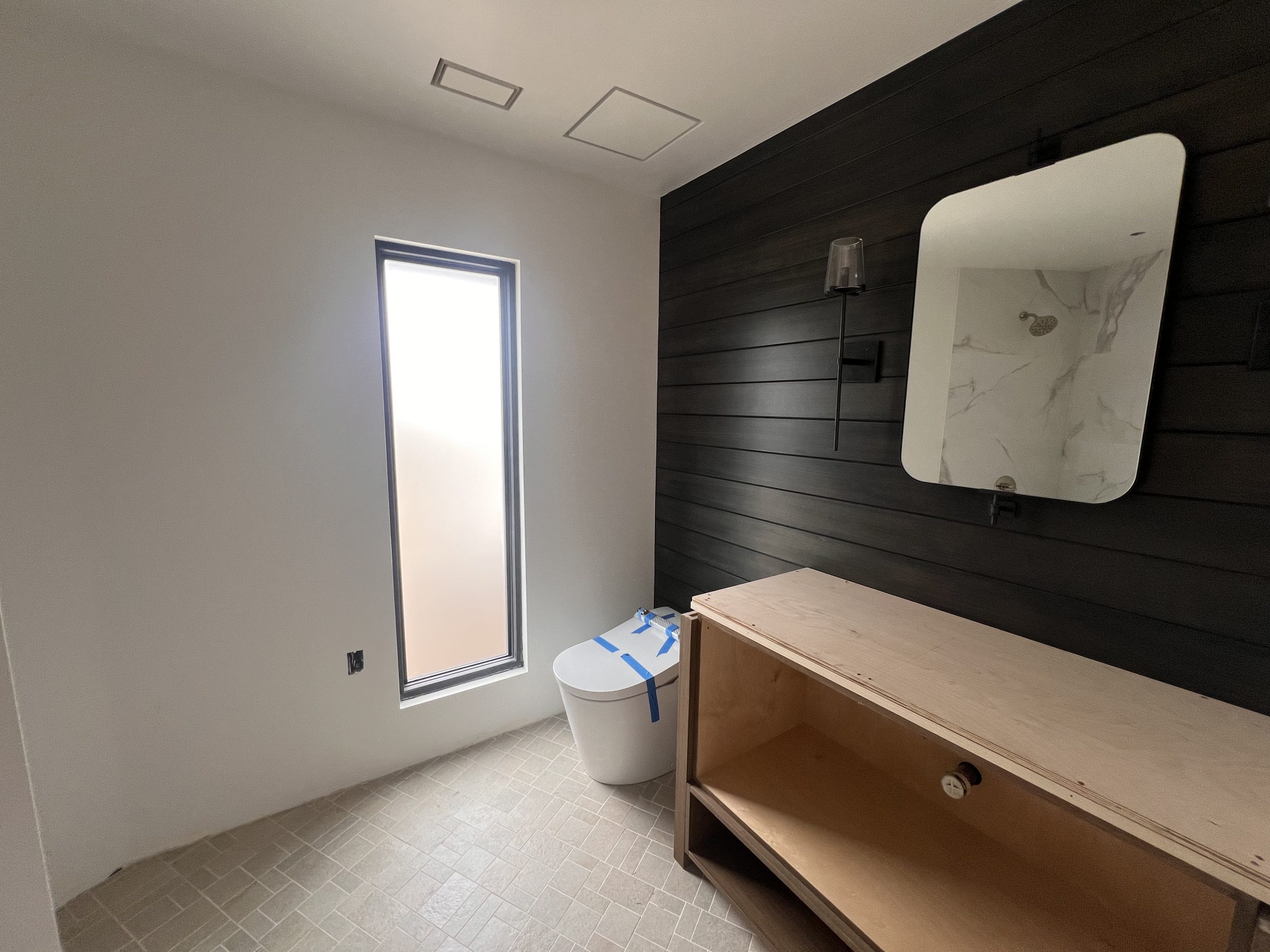 Finished bathroom with smooth drywall and a shiplap accent feature wall, clean transitions between tile and drywall, North County