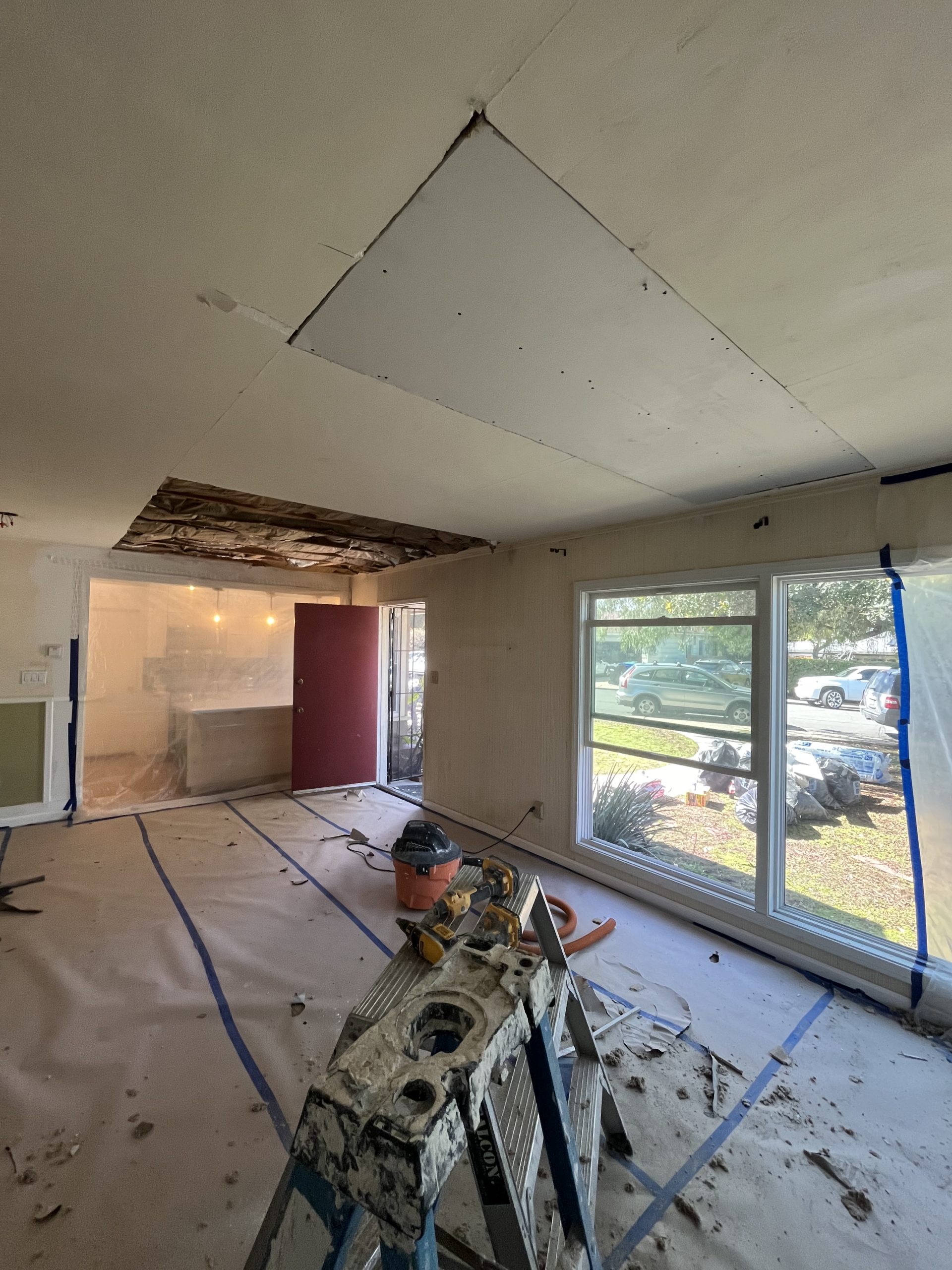 Room mid-project with old drywall removed and fresh boards being installed on walls, San Diego