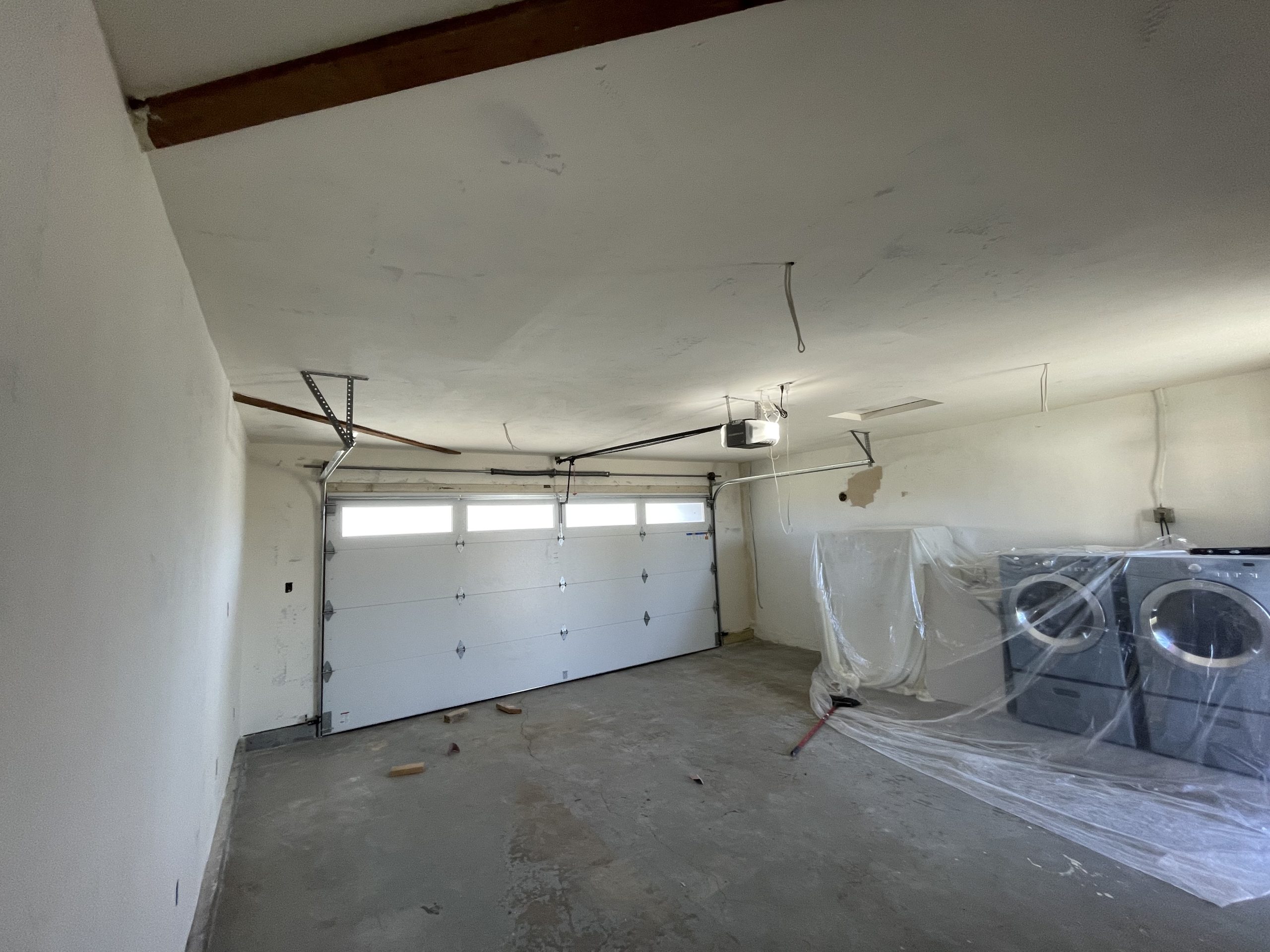 Completed garage with smooth white drywall ceiling and walls throughout, garage door visible at far end, East County San Diego