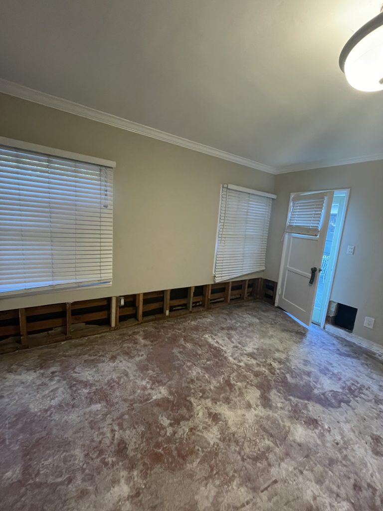 Living room with flood-cut openings along the lower walls, drywall removed to expose the framing after water mitigation